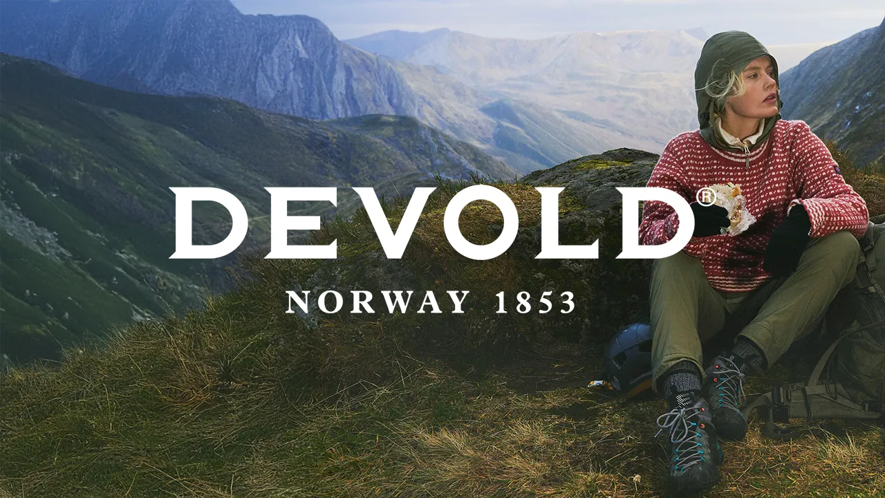 Devold outdoor lifestyle image featuring a hiker wearing sustainable wool apparel in the Nordic mountains, reflecting the brand’s heritage and Swan Ecolabel commitment