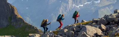 Backpacking hikers wearing Deuter Aircontact bags, while walking along a mountain trail in Senja, Norway.