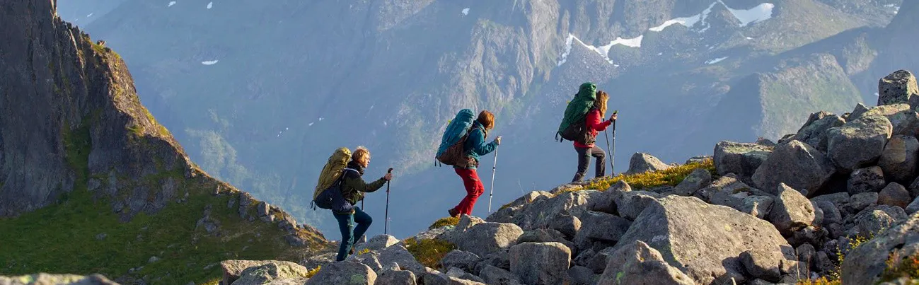 Backpacking hikers wearing Deuter Aircontact bags, while walking along a mountain trail in Senja, Norway.